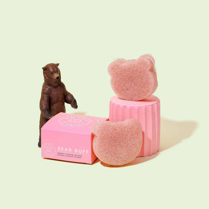 A pink Konjac sponge shaped like a bear, displayed next to its packaging box with a bear figurine.